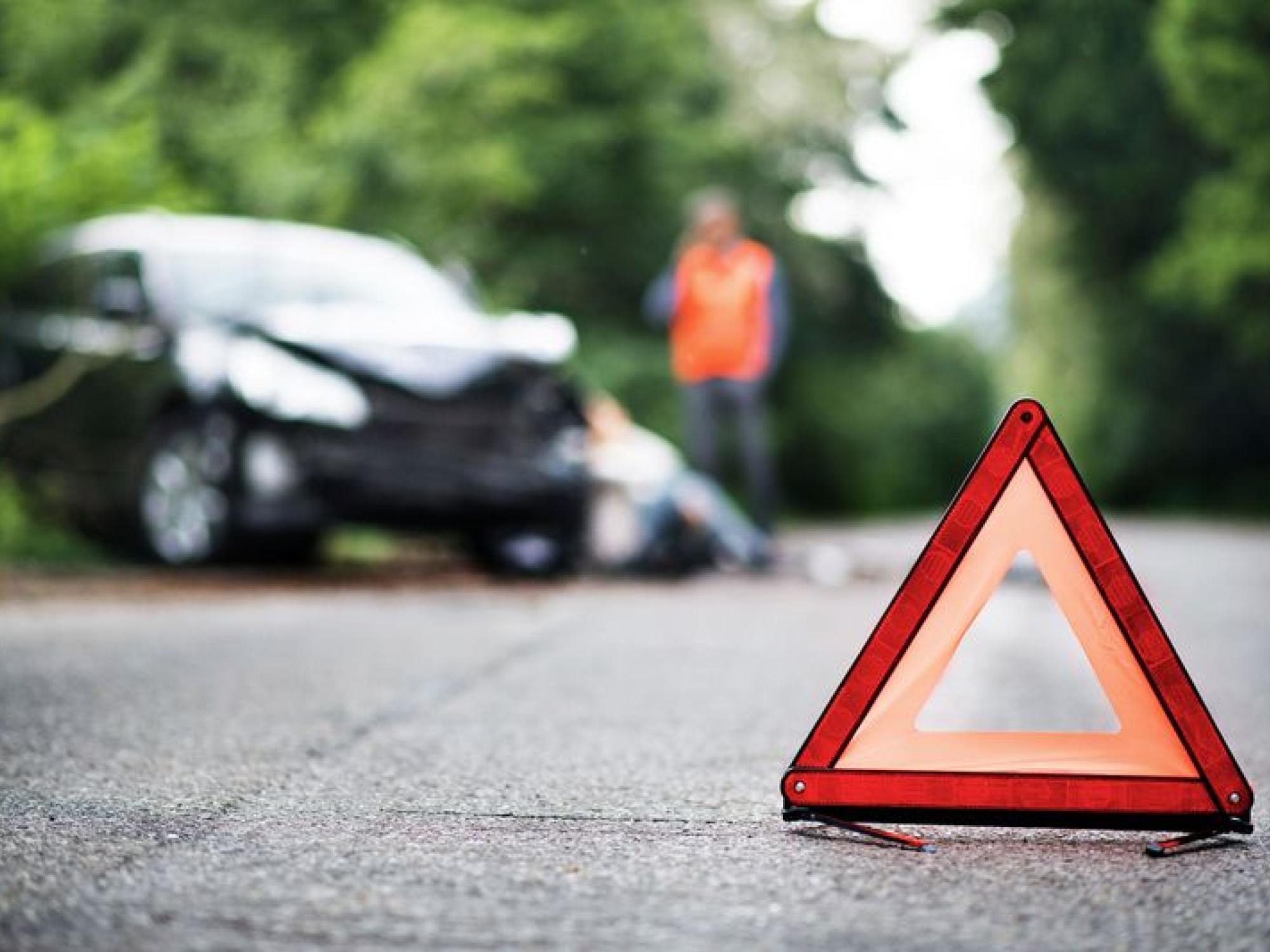 warning triangle with a broken car in the background